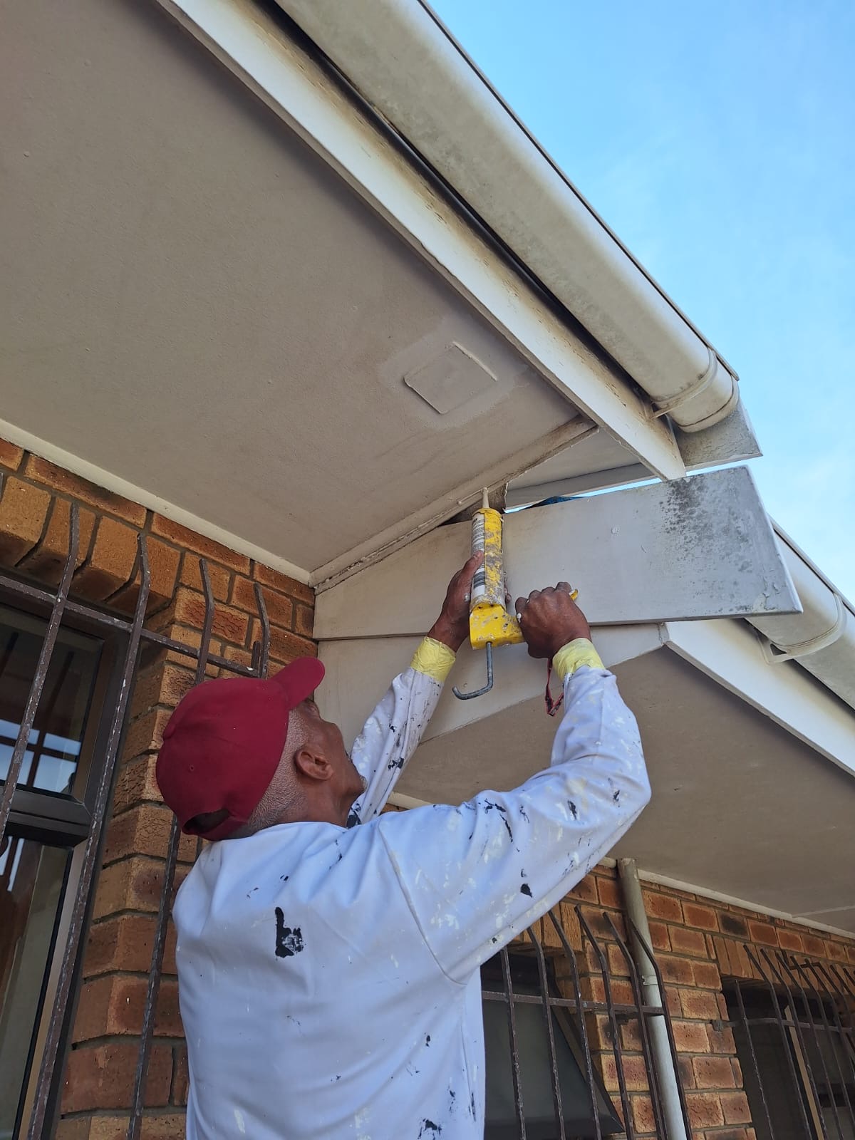 MJK Solutions painter sealing a joint beneath exterior fascia boards before painting